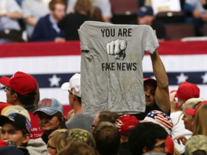A Trump supporter holds up a T-shirt blasting "fake news" so media could see before a rally address by President Donald Trump Thursday, Oct. 4, 2018, in Rochester, Minn. (AP Photo/Jim Mone)