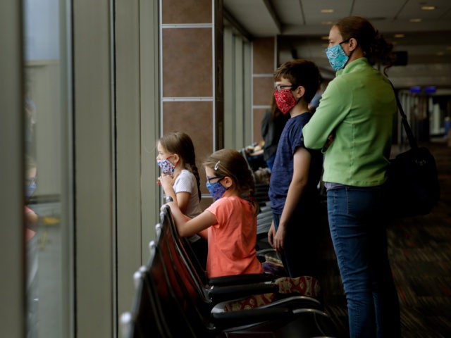 A family wearing masks wait to board a Southwest Airlines flight Sunday, May 24, 2020 at Kansas City International airport in Kansas City, Mo. About three dozen passengers boarded the plane with a capacity of nearly 150 as people are opting not to travel on the normally busy Memorial Day …