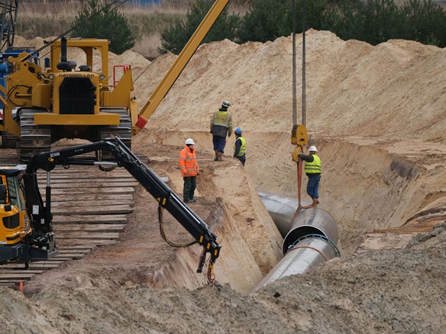 LUBMIN, GERMANY - MARCH 26: Workers lower sections of pipe along the construction route of the Eugal gas pipeline on March 26, 2019 near Lubmin, Germany. The Eugal gas pipeline will transport natural gas arriving from Russia through the Nord Stream 2 pipeline 480km across eastern Germany, from Lubmin on the Baltic Sea to the Czech border.  (Photo by Sean Gallup/Getty Images)