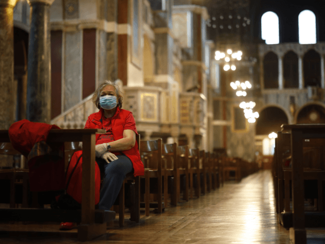 TOPSHOT - A single worshipper wearing a surgical mask sits on a pew in Westminster Cathedr