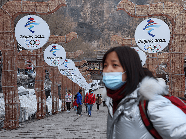 People wear protective masks as they walk front the logos of the 2022 Beijing Winter Olympics at Yanqing Ice Festival on February 26, 2021 in Beijing, China. The Festival comes at the final day of the Chinese Lunar New Year celebrations. (Photo by Lintao Zhang/Getty Images)