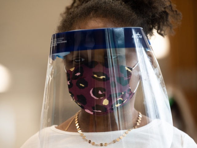 LOUISVILLE, KY - MARCH 17: A child wearing a face shield and mask stands in the cafeteria of Medora Elementary School on March 17, 2021 in Louisville, Kentucky. Today marks the reopening of Jefferson County Public Schools for in-person learning with new COVID-19 procedures in place. (Photo by Jon Cherry/Getty Images)