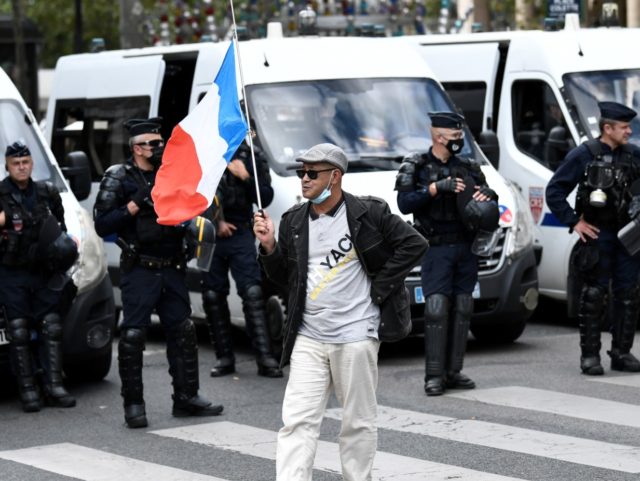 A demonstrator carries a french flag past a line of gendarmes, during protests against the compulsory Covid-19 vaccination for certain workers and the mandatory use of the health pass called for by the French government outside the Council d'Etat and Conseil Constitutionnel in Paris on August 5, 2021. - The …