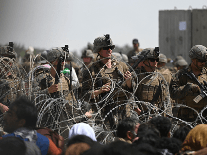 US soldiers stand guard behind barbed wire as Afghans sit on a roadside near the military part of the airport in Kabul on August 20, 2021, hoping to flee from the country after the Taliban's military takeover of Afghanistan. (Photo by Wakil KOHSAR / AFP) (Photo by WAKIL KOHSAR/AFP via …