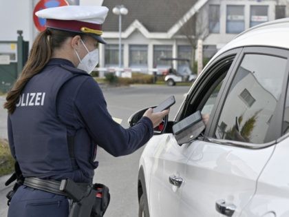 An Austrian police officer checks a driver's digital vaccination certificate on a smartphone during a traffic control in Voesendorf, district Moedling, Austria, on November 16, 2021, during the ongoing coronavirus (Covid-19) pandemic. - Austrian Chancellor Schallenberg told AFP that the "difficult" lockdown imposed on November 15 on unvaccinated people had …