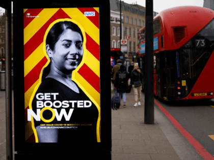 A red London bus stops at a bus stop displaying a government advertisement promoting the NHS covid-19 vaccine Booster program in London on December 17, 2021. - Britain yesterday recorded a second consecutive record daily number of new Covid infections at more than 88,000 but the government has so far …