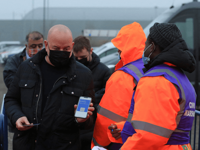 Covid-19 Marshalls check the status of a fan's NHS Covid Pass as they arrive to attend the English Premier League football match between Leeds United and Arsenal at Elland Road in Leeds, northern England on December 18, 2021. (Photo by Lindsey Parnaby / AFP) (Photo by LINDSEY PARNABY/AFP via Getty …