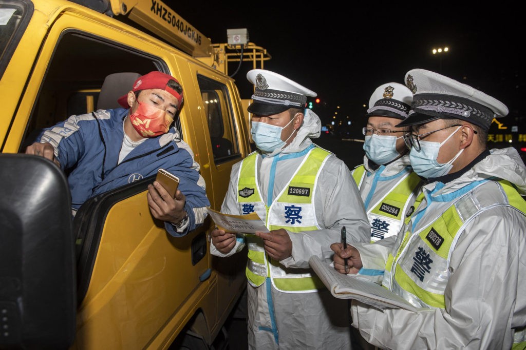 This photo taken on December 18, 2021 shows police officers wearing personal protective equipment (PPE) checking information with a truck driver (L) at a check point in Ningbo, in China's eastern Zhejiang province. - China OUT (Photo by AFP) / China OUT (Photo by STR/AFP via Getty Images)