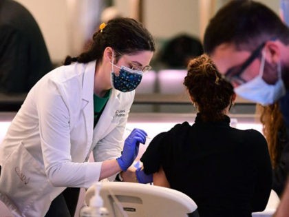 A woman receives her Covid-19 vaccination at a pop-up clinic in the international arrivals area of Los Angeles International Airport in Los Angeles, California, on December 22, 2021. - The clinic at the airport offers free vaccinations and boosters for holiday travelers on December 22 and on December 29. Los …