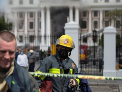 Firefighters walk out of the area, as a fire carries on burning in the South African Parliament buildings, in Cape Town on January 2, 2022. - A major fire raging on January 2, 2022, in South Africa's seat of parliament in Cape Town had not been brought under control by …