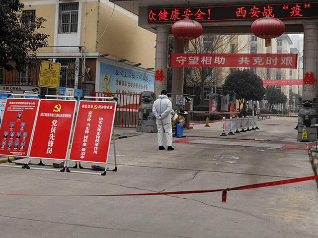 A man in a protective suit stands guard at an entrance of a residential compound in Xi'an