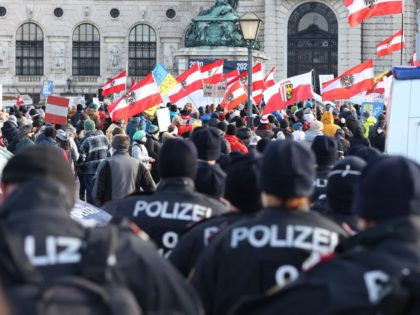 Policemen look on as people carry Austrian flags as they demonstrate against the Austrian government's measures taken in order to limit the spread of the coronavirus during a protest on January 8, 2022 in Vienna, amid the novel coronavirus / COVID-19 pandemic. - Austria OUT (Photo by FLORIAN WIESER / …