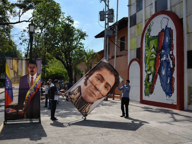 TOPSHOT - Two men carry banners with images of Venezuelan President Nicolas Maduro (L) and national hero Simon Bolivar, before a press conference by Jorge Arreaza, the candidate of the ruling United Socialist Party of Venezuela (PSUV) for the governorship of Barinas State who was defeated in Sunday's re-run gubernatorial …