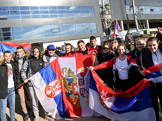 People holds Serbian national flags as they pose while waiting outside the VIP exit of Belgrade