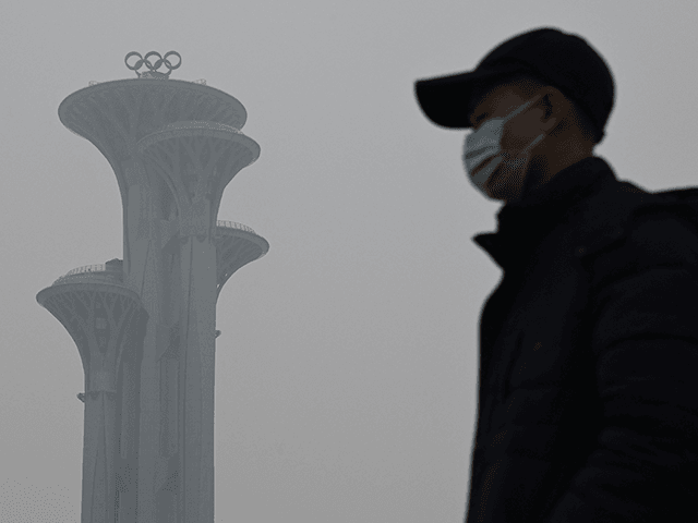A man walks in the Olympic Park during a smoggy day in Beijing on January 24, 2022. (Photo