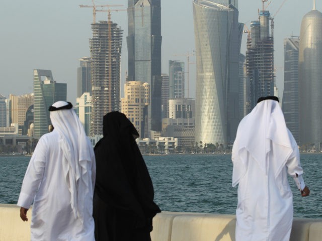 DOHA, QATAR - OCTOBER 24: Men and women wearing traditional Qatari clothing visit the waterfront along the Persian Gulf across from new, budding financial district skyscrapers on October 24, 2011 in Doha, Qatar. Qatar will host the 2022 FIFA World Cup football competition and is slated to tackle a variety …