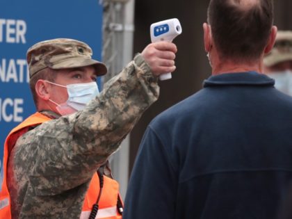 An Illinois National Guardsman takes the temperature of residents arriving at a mass COVID-19 vaccination center set up in a parking lot outside of the United Center, home to the Chicago Bulls and Blackhawks, on March 10, 2021 in Chicago, Illinois. The site, which opened at full capacity today, expects …