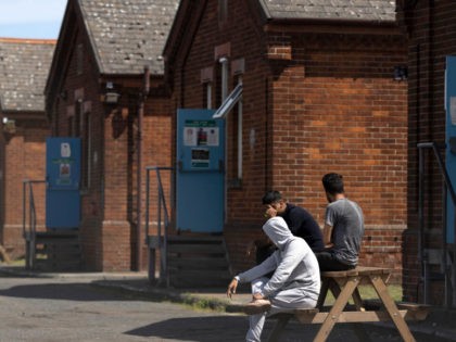 FOLKESTONE, ENGLAND - JUNE 11: Asylum seekers sit outside their accommodation at Napier Ba
