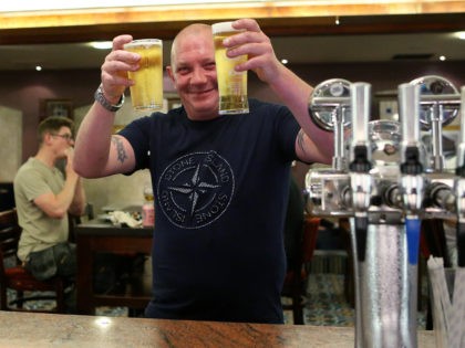 MANCHESTER, ENGLAND - JULY 19: A man poses for a photograph with his drinks after being served at the bar at Wetherspoons pub The Moon Under Water on July 19, 2021 in Manchester, England. As of 12:01 on Monday, July 19, England will drop most of its remaining Covid-19 social …