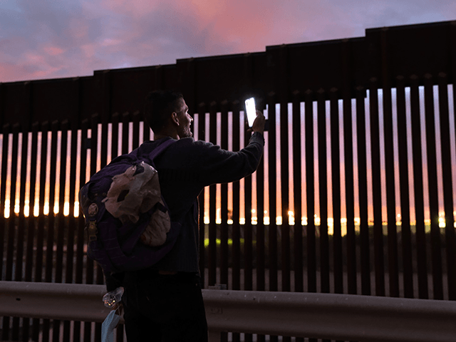 YUMA, ARIZONA - DECEMBER 10: A relieved Venezuelan immigrant speaks with his wife on a video call after he passed through a gap in the U.S.-Mexico border wall after having traveled from South America to the United States on December 10, 2021 in Yuma, Arizona. Yuma has seen a surge …
