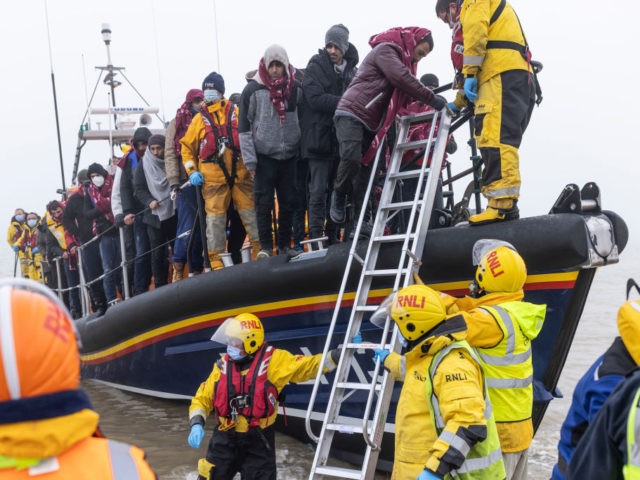 DUNGENESS, ENGLAND - DECEMBER 19: Migrant men are aided ashore by members of the R.N.L.I. and Border Force officials after making the journey across the English Channel from France during heavy fog on December 19, 2021 in Dungeness, England. There has been over a threefold increase in the number of …