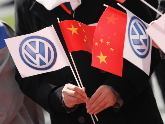 WOLFSBURG, GERMANY - APRIL 23: Guests hold Chinese and Volkswagen logo flags before the arrival of Chinese Premier Wen Jiabao next at the Volkswagen factory on April 23, 2012 in Wolfsburg, Germany. Volkswagen CEO Martin Winterkorn and representatives of Chinese companies signed an agreement later in the day to extend …