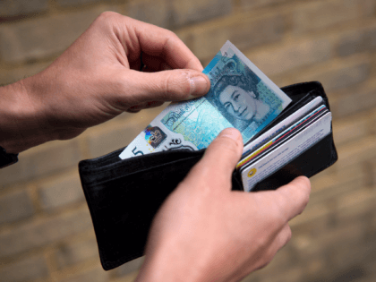 In this posed photograph a person is pictured holding a wallet containing a £5 (five pound) note in London on October 7, 2016. The Bank of England is "looking into" what caused the pound to slump more than six percent against the dollar in less than ten minutes Friday, a …