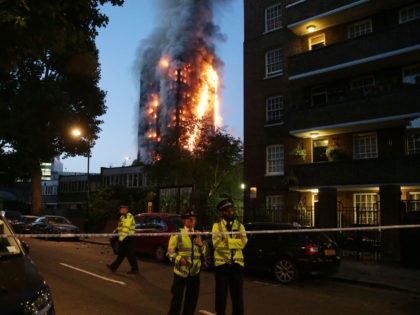 TOPSHOT - Police man a security cordon as a huge fire engulfs the Grenfell Tower early June 14, 2017 in west London. - The massive fire ripped through the 27-storey apartment block in west London in the early hours of Wednesday, trapping residents inside as 200 firefighters battled the blaze. …