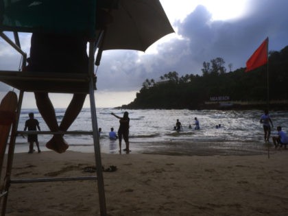 A lifeguard keeps watch as Indian tourists spend the evening on a beach in Goa, India, Tuesday, Aug. 31, 2021. (AP Photo/Manish Swarup)