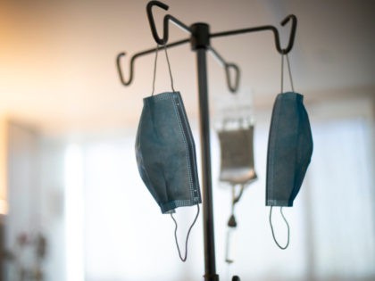In this Aug. 8, 2020, photo a patient receives an IV drip as face masks hang from an IV pole at a hospital in Portland, Ore. (AP Photo/Jenny Kane)