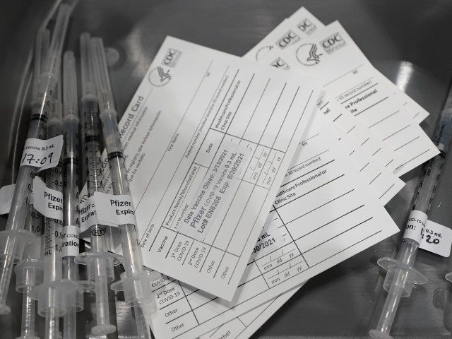 FILE - Syringes with doses of the Pfizer COVID-19 vaccine are shown next to vaccination cards March 13, 2021, in Seattle. The District of Columbia government is imposing a series of COVID-19 vaccine mandates as it intensifies virus protocols in response to spiraling infection numbers and the march of the …