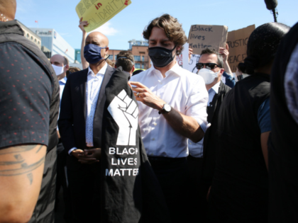 Canadian Prime Minister Justin Trudeau (C) holds a t-shirt he was handed while taking part