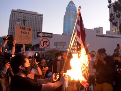 TOPSHOT - A man burns an upsidedown US flag as protesters gather in downtown Los Angeles on May 27, 2020 to demonstrate after George Floyd, an unarmed black man, died while being arrested by a police officer in Minneapolis who pinned him to the ground with his knee. - Outrage …