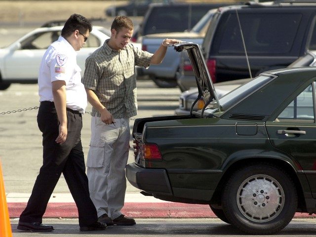 A security guard looks into the trunk of a car before allowing it to park in the short ter