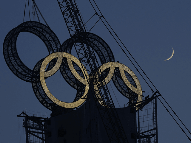 A worker labors to assemble the Olympic Rings onto of a tower on the outskirts of Beijing, China, Wednesday, Jan. 5, 2022. Beijing will host the Winter Olympics in a month's time, making it the world's first dual Olympic city having hosted both the Summer and Winter games. (AP Photo/Ng …
