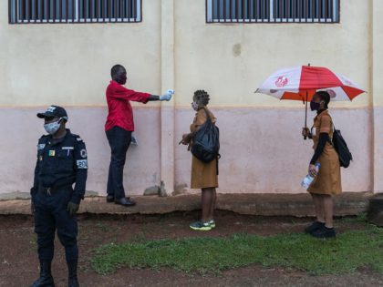 A staff member (2nd L) of the Lycée Bilingue School measures the temperature of a student in Yaoundé, Cameroon, on June 1, 2020. - Cameroon's schools and universities reopened on Monday as the government was criticised over weak measures to combat the spread of coronavirus in one of the worst-affected …
