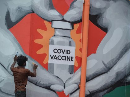 Workers give finishing touches to a huge mural made on the facade of the Tambaram railway station, to create awareness and promote Covid-19 coronavirus vaccination in Chennai on July 4, 2021. (Photo by Arun SANKAR / AFP) (Photo by ARUN SANKAR/AFP via Getty Images)