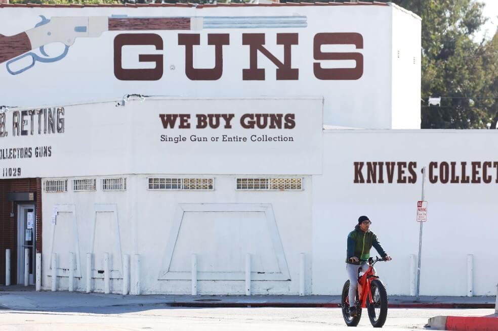CULVER CITY, CALIFORNIA - MARCH 24: A cyclist rides past the Martin B. Retting, Inc. guns store as the coronavirus pandemic continues on March 24, 2020 in Culver City, California. L.A. County Sheriff Alex Villanueva stated today that gun stores are nonessential businesses and must close as part of the ordered shuttering of L.A. County shops in efforts to stem the spread of COVID-19. (Photo by Mario Tama/Getty Images)