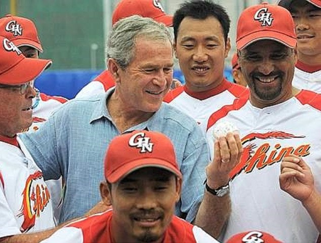 US President George W. Bush (C) holds a signed baseball while posing with Chinese baseball team coach Jim Lefebvre (L) of the US and members of the Chinese Olympic baseball team ahead of a practice 2008 Beijing Olympic Games baseball game between the US and China at the Wukesong Culture and Sports Center Baseball Stadium in Beijing on August 11, 2008. Bush, who earlier in the morning took in the swimming competition, joined thousands of boisterous Chinese fans for a late night match up on August 10 between Yao Ming-led China and the NBA-laden Team USA in men's basketball at the Beijing Olympics. AFP PHOTO/Mandel NGAN (Photo credit should read MANDEL NGAN/AFP via Getty Images)