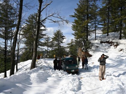 Stranded local tourists wait along a road following a blizzard that started on January 7 and led to visitors being trapped in vehicles along the roads to the resort hill town of Murree, some 70 Kms northeast of Islamabad on January 9, 2022. - Army rescuers on January 9 cleared …