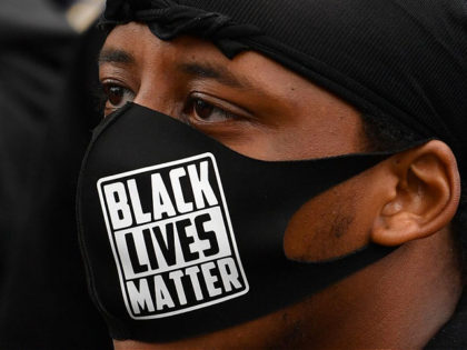 TOPSHOT - Protesters, some wearing PPE (personal protective equipment), of a face mask as a precautionary measure against COVID-19, hold placards as they attend a demonstration in Manchester, northern England, on June 6, 2020, to show solidarity with the Black Lives Matter movement in the wake of the killing of …