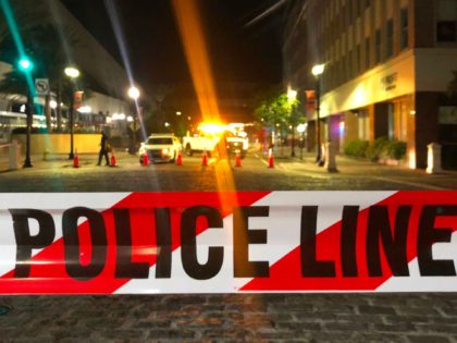 This photo shows a police car behind police tape blocking a street leading to the Jacksonville Landing area in downtown Jacksonville, Florida, August 26, 2018, where three people were killed, including the gunman, and 11 others wounded. - Two people were killed and 11 others wounded on August 26 when …