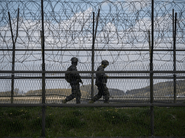 South Korean soldiers patrolling along a barbed wire fence at the Demilitarized Zone with