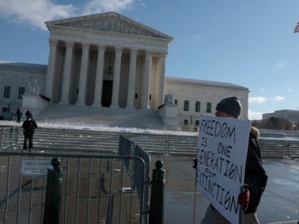 WASHINGTON, DC - JANUARY 07: A protester holds a sign that reads "Freedom is one generation from Extinction" as he walks by the U.S. Supreme Court on Capitol Hill on January 07, 2022 in Washington, DC. Today the Justices of the Supreme Court are hearing arguments against U.S. President Joe …