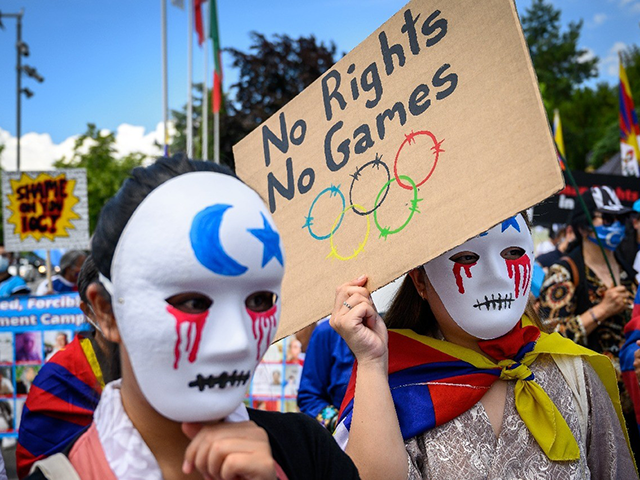 Tibetan and Uyghur activists hold placards and wear masks during a protest against Beijing