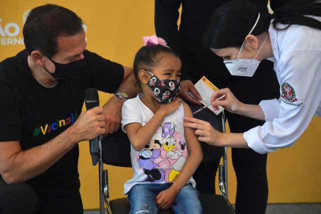 A child receives a Covid-19 vaccine in Brazil's Sao Paulo with local governor Joao Doria (