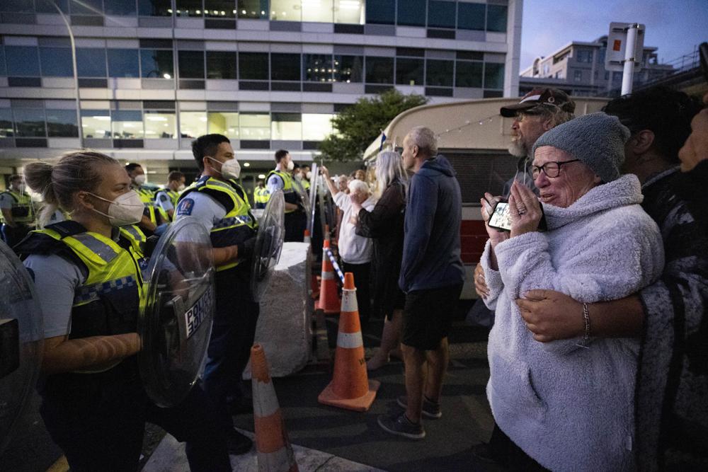 Police and protesters clash in Wellington, New Zealand, Tuesday, Feb. 22, 2022, as police tightened a cordon around a protest convoy that has been camped outside Parliament for two weeks. The protesters, who oppose coronavirus vaccine mandates and were inspired by similar protests in Canada, appear fairly well organized after trucking in portable toilets, crates of donated food, and bales of straw to lay down when the grass turned to mud. (George Heard/New Zealand Herald via AP)