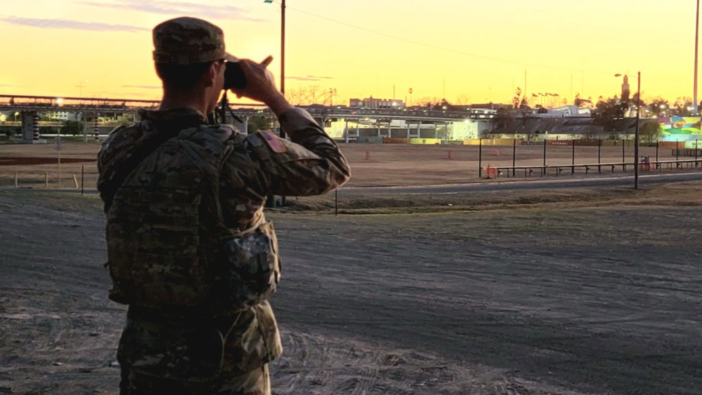 As the sun sets in Eagle Pass, a Texas Guardsman continues to maintain security at a Rio Grande migrant crossing point. (Bob Price/Breitbart Texas)
