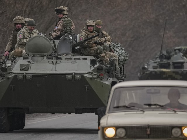 Ukrainian servicemen sit atop armored personnel carriers driving on a road in the Donetsk region, eastern Ukraine, Thursday, Feb. 24, 2022. Russian President Vladimir Putin on Thursday announced a military operation in Ukraine and warned other countries that any attempt to interfere with the Russian action would lead to "consequences you have never seen."