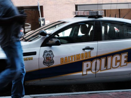 A person walks past a police car on July 28, 2019 in Baltimore, Maryland. (Photo by Spencer Platt/Getty Images)